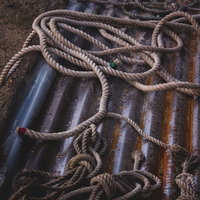 廃墟に放置された朽ちたロープと錆びた鉄管の写真