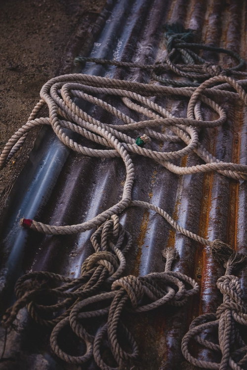 廃墟に放置された朽ちたロープと錆びた鉄管の写真