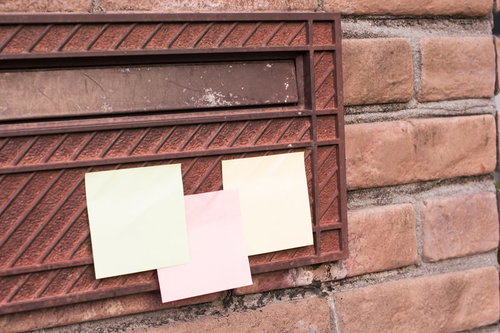 赤茶色のレンガ壁にクリームと淡いピンクの2枚の付箋が貼られた写真