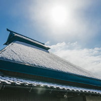 屋根に薄っすら雪が残る瓦葺きの和建築、晴れた冬の日中の写真