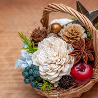 白い花と赤い実が入った籠のフラワーアレンジメントの写真