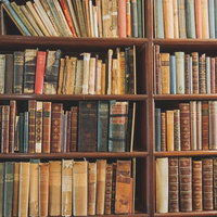 古い本が多数並ぶ木製の洋書の本棚の写真
