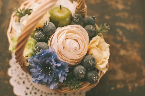 ピンクや青紫の花と緑の実が入った籐のバスケットアレンジ