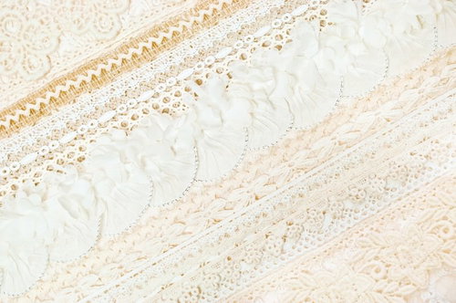 白い布の上に重なるレースとビーズ装飾のテクスチャー