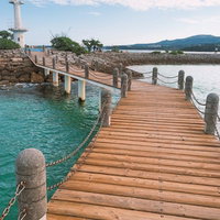 石の柱とチェーンの手すりがある木の桟橋と白い灯台の写真