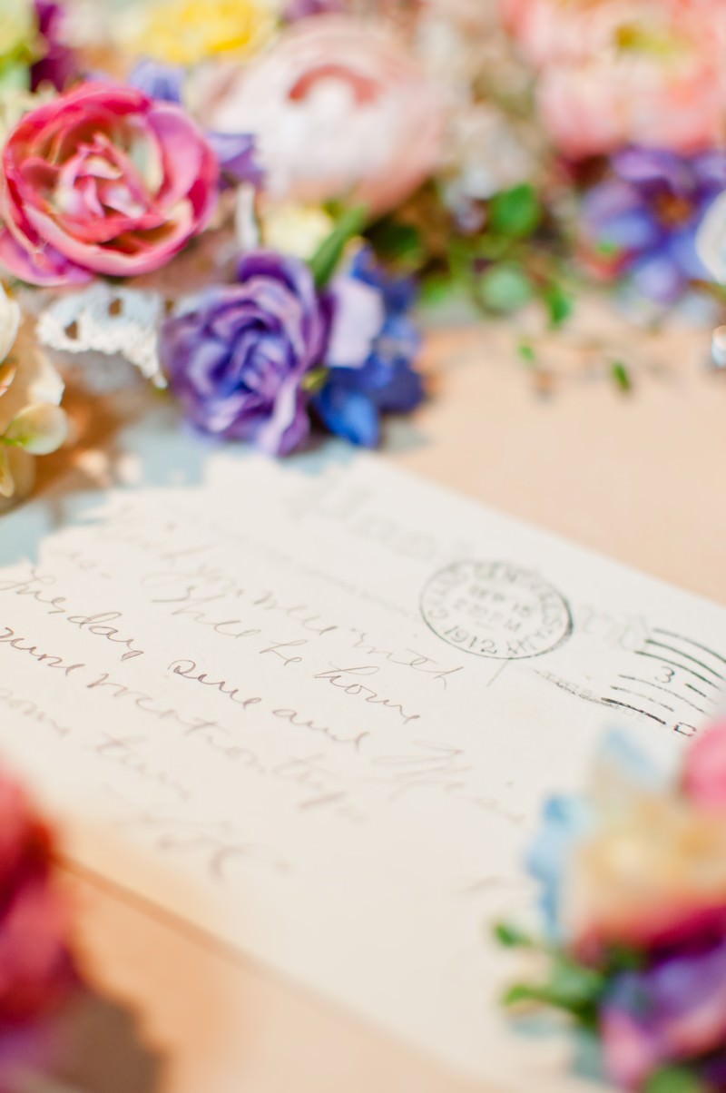ピンク・パープルの造花に囲まれた手書きメッセージの手紙