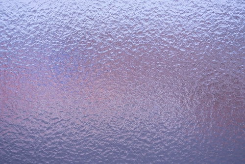 紫やピンクの光が当たる曇りガラス表面のテクスチャー