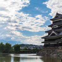 松本城の天守閣と清流、青空に映える国宝の城の写真