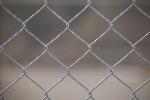 菱形の網目が規則的に並ぶ金属フェンスのテクスチャー