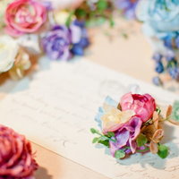 手紙風の紙の上に並ぶカラフルな造花の写真