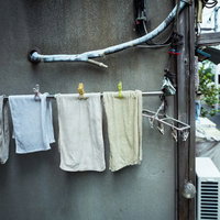 古いアパートの外壁に吊るされたタオルと洗濯物の写真