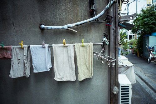 古いアパートの外壁に吊るされたタオルと洗濯物の写真