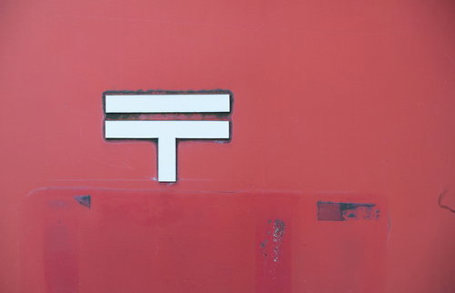 赤い郵便ポストの〒マーク、白く描かれた郵便記号