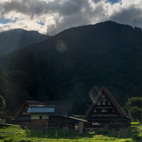雲間から差す光芒と南砺市の菅沼集落の合掌造りの写真