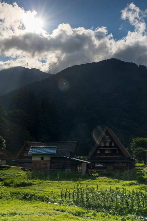 雲間から差す光芒と南砺市の菅沼集落の合掌造り