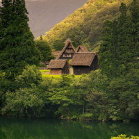 川面に映りこむ木々を見下ろす菅沼集落の夕焼けの写真