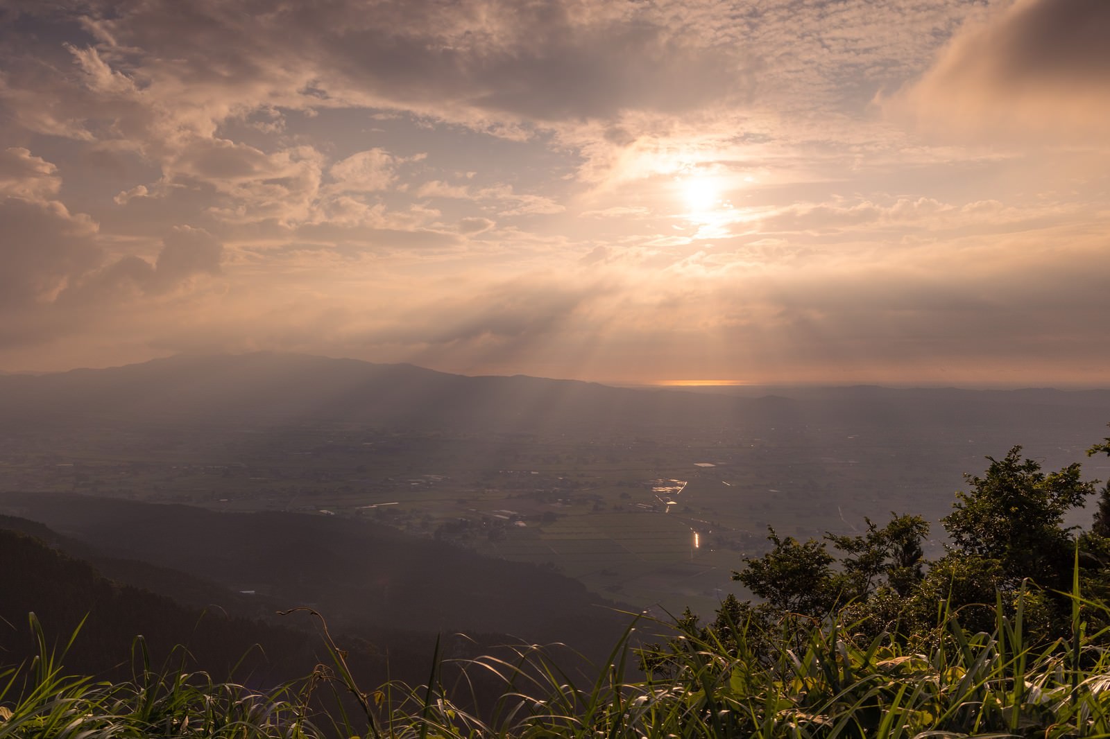 雲間から差し込む天使の梯子が散居村を照らす夕暮れの風景