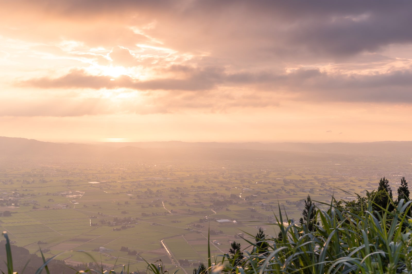 雲間から差し込む薄明光線に照らされた夕暮れの散居村風景