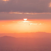 沈む夕日と散居村が点在する富山県南砺市の田園風景の写真