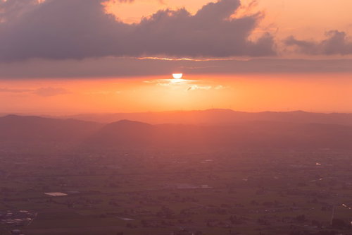 沈みゆく夕日と黄昏時の散居村、富山県南砺市の田園風景