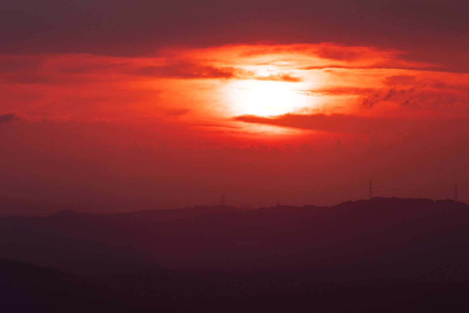 オレンジから赤のグラデーションの空に沈む太陽と山のシルエット
