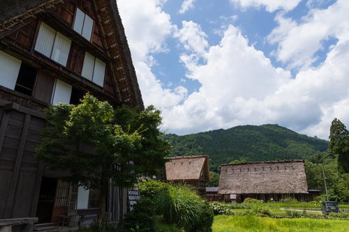 白川郷の合掌造りの家屋が青空の下に立つ