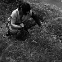 刀を肩にかけて川沿いの竹林に座り込む山賊の写真
