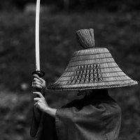 編み笠を被った侍が日本刀を高く上げて上段の構えを見せる姿の写真