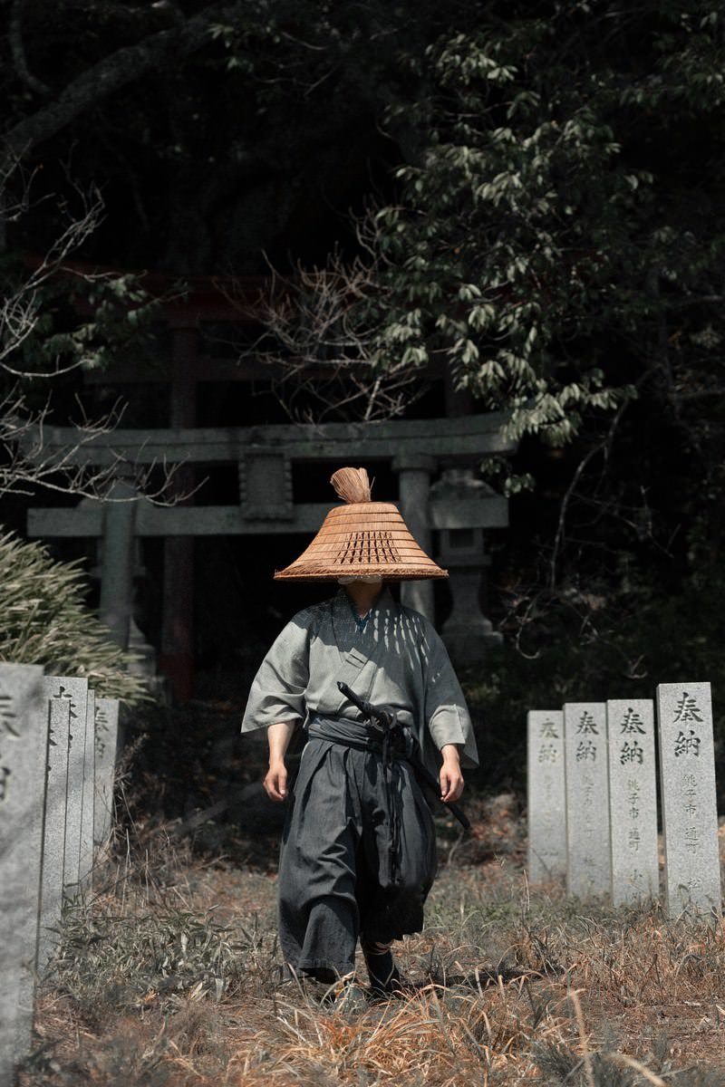 大和田稲荷神社の鳥居前で編み笠をかぶり刀を携えた侍姿の男性［モデル：まーこ］