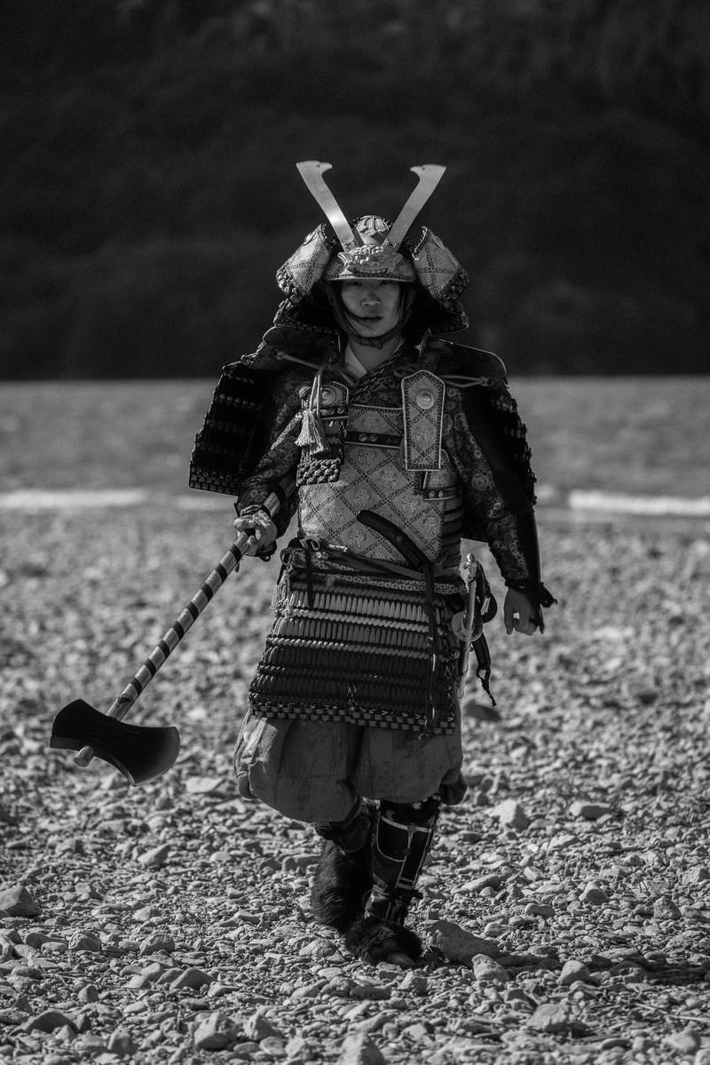 黒い大鎧と両角兜を身につけ、斧を握る武士の姿［モデル：まーこ］