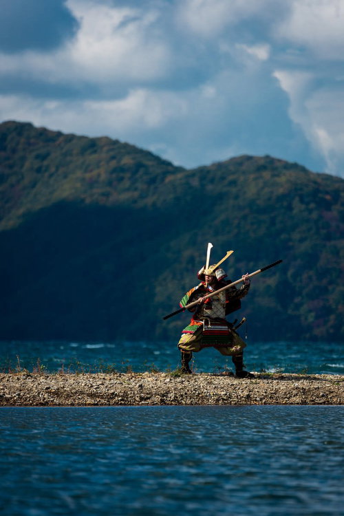 湖畔で棍棒を構える大鎧を纏う武士、山々を背景に戦闘態勢