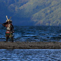 湖畔の中州で大鎧を纏う武士が槍を構える戦国時代の武将の写真