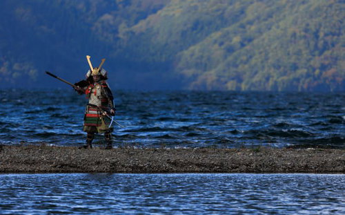 湖畔の中州で大鎧を纏う武士が槍を構える戦国時代の武将