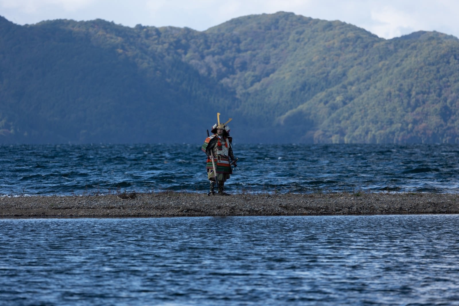 大鎧を着た侍が中州の湖畔に棍棒を持って立つ［モデル：まーこ］