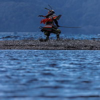 中州の河原で刀を振り下ろす大鎧を纏った侍の写真