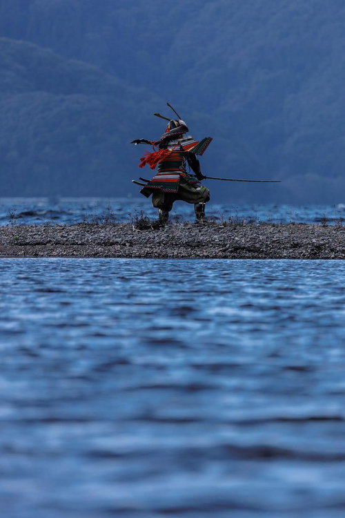 中州の河原で刀を振り下ろす大鎧を纏った侍