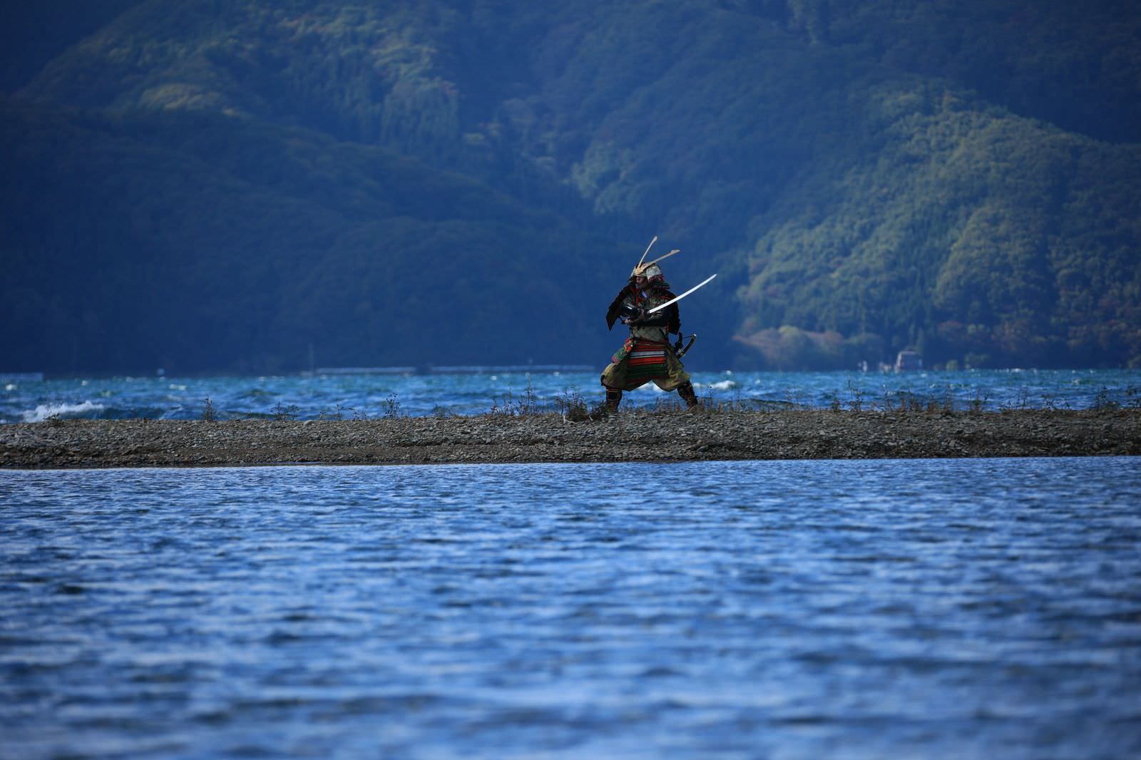 湖の中州で大鎧に身を包み刀を構える侍の男性［モデル：まーこ］