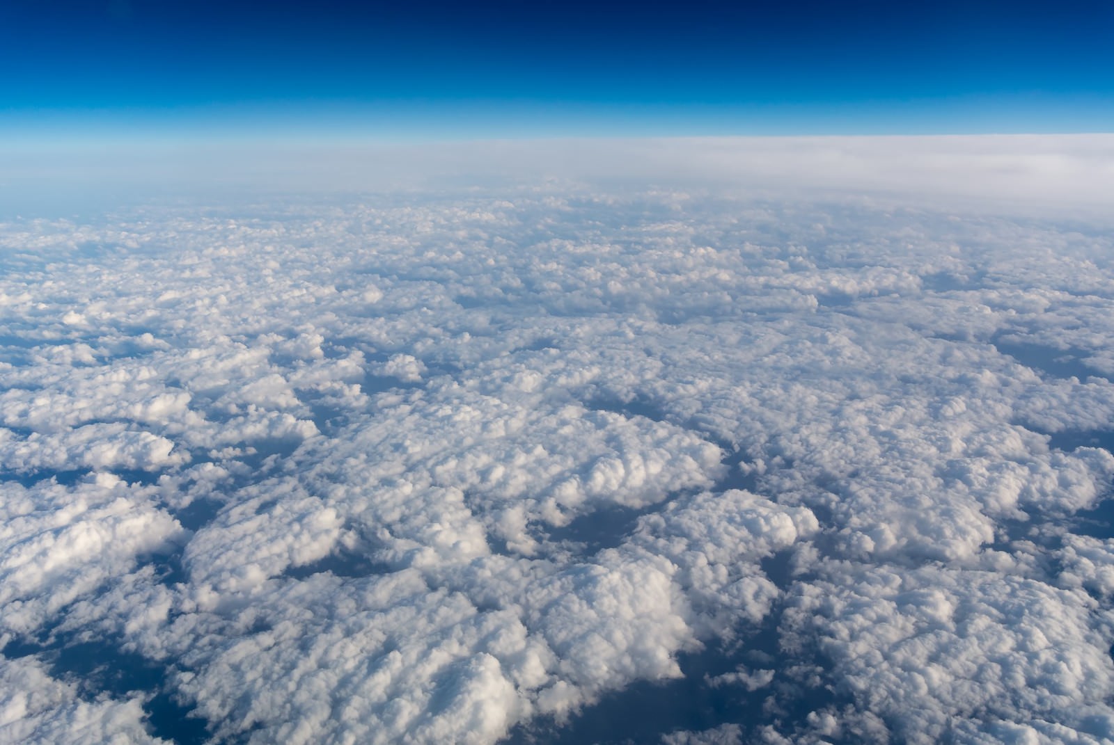 飛行機の上から見た眼下の白い積雲と青い空の風景