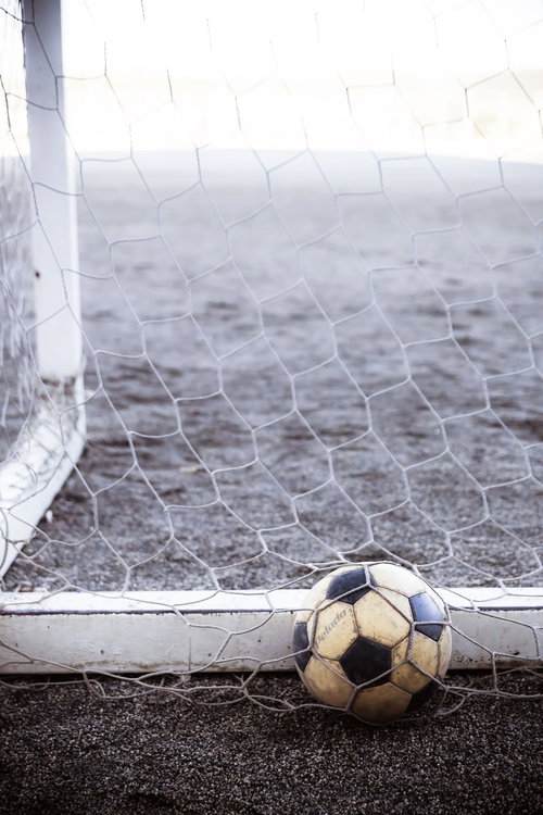 白いネットの下に置かれた使い込んだサッカーボール