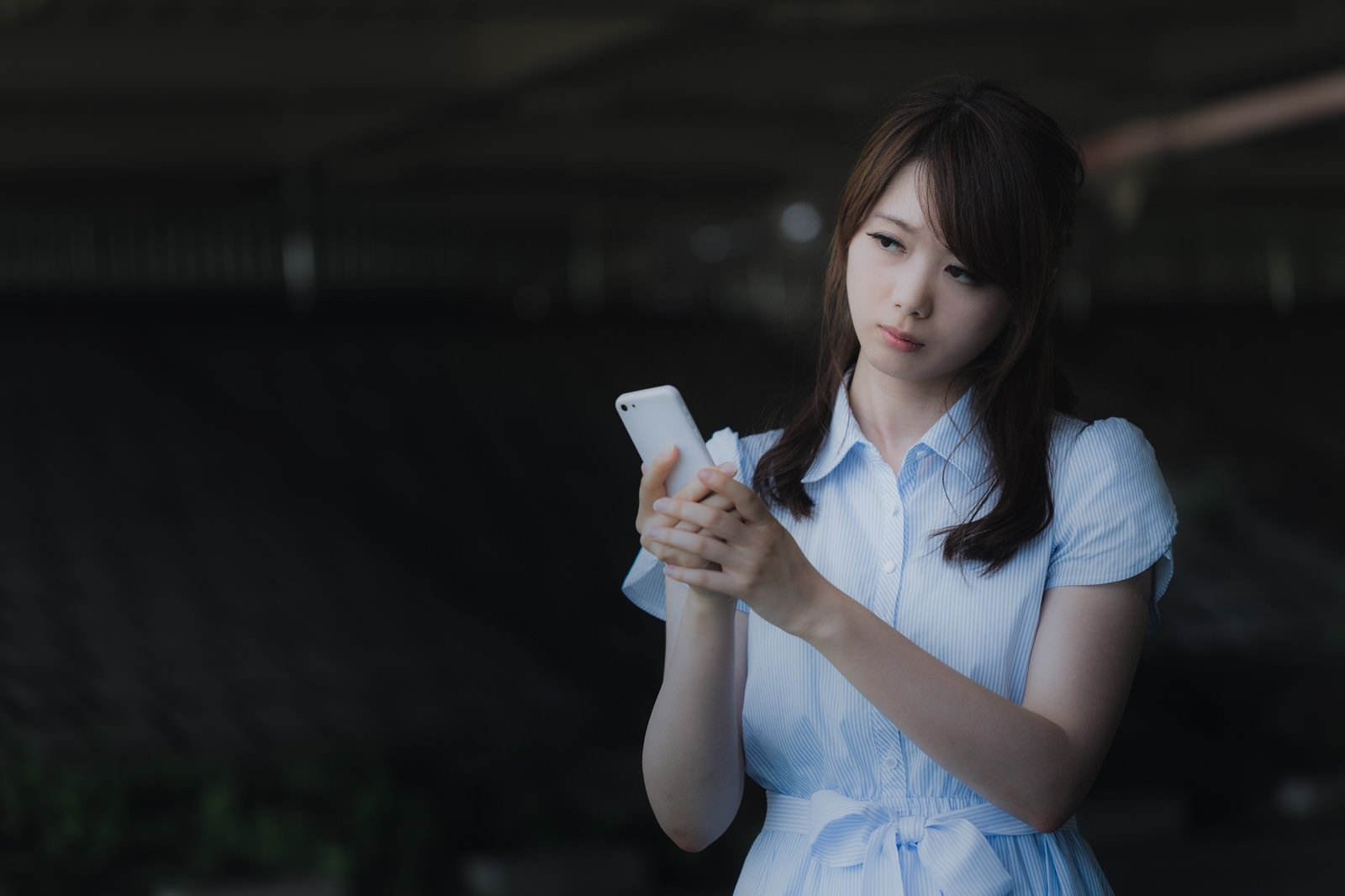 圏外のスマホ画面を見つめる女性［モデル：モデルリリース］
