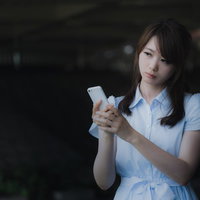 ずっと圏外表示のまま変わらないスマホを見つめる女性の写真