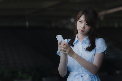 ずっと圏外表示のまま変わらないスマホを見つめる女性