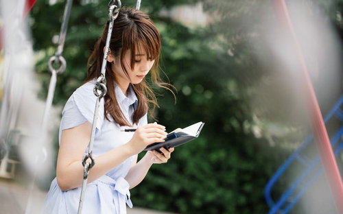 公園のブランコで手帳に向き合い悩む女性の心理描写