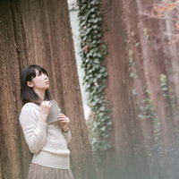 森に迷い込んだ読書美女が上を見つめる白いセーターの写真
