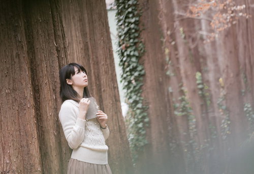 森に迷い込んだ読書美女が上を見つめる白いセーター
