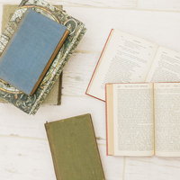 床に置かれた洋書と古地図の装飾本の積み重ねと読書風景の写真