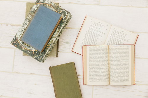 床に置かれた洋書と古地図の装飾本の積み重ねと読書風景