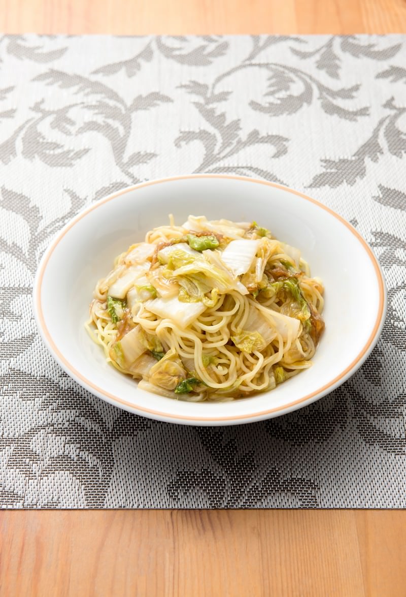 白い深皿に黄色い細麺と白菜やネギが混ざった焼きそばが盛られている