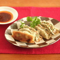 しま模様の皿に盛った餃子と味噌だれの写真