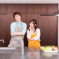 今日の夕食レシピは何にしようか？と考える夫婦の写真